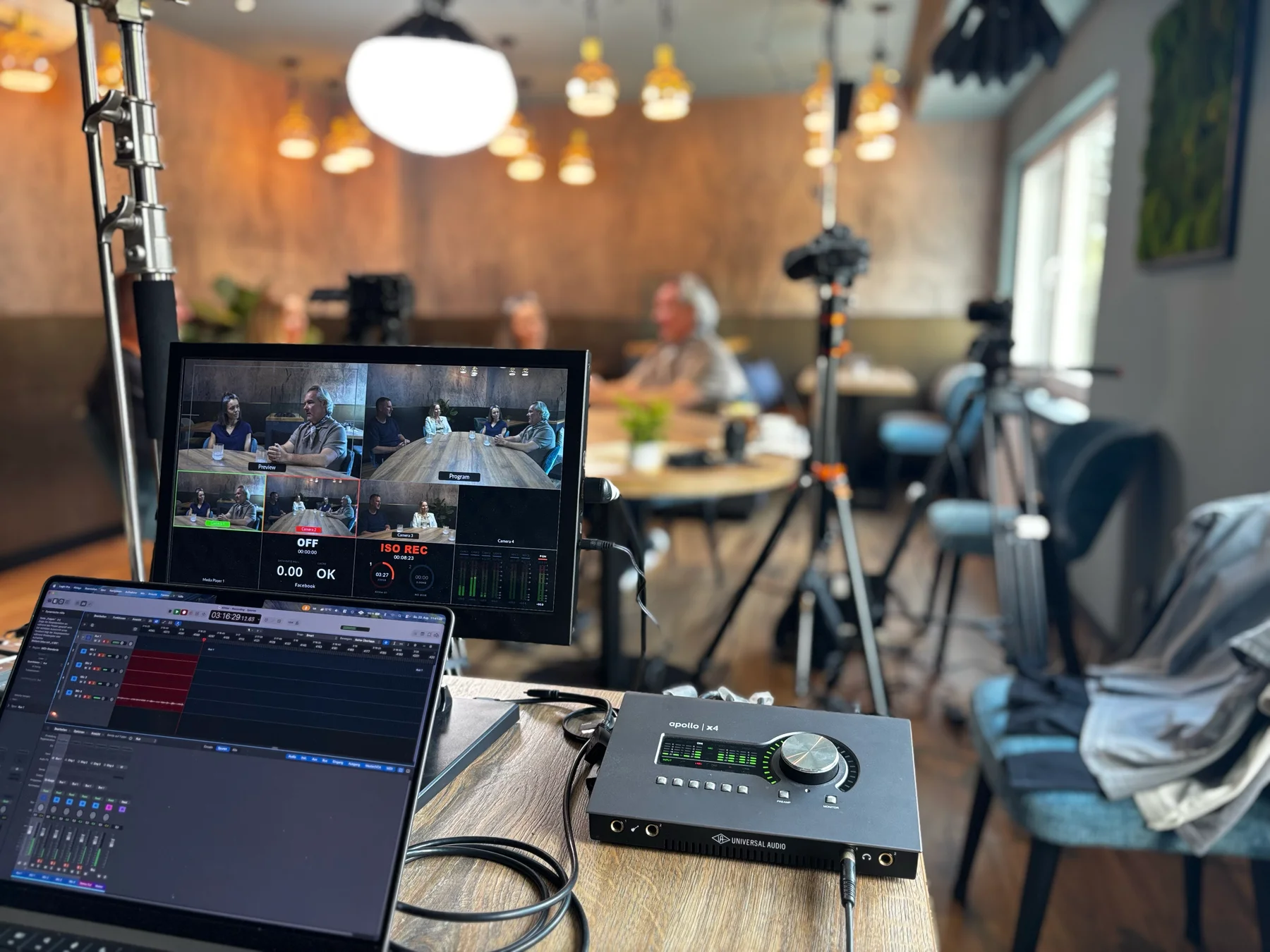 Podcast-Aufzeichnung vor Ort mit Bildmonitor, Laptop und Audiointerface im Vordergrund